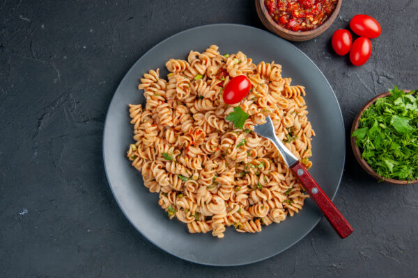 top-view-rotini-pasta-with-cherry-tomato-fork-plate-parsley-tomato-sauce-bowls-dark-surface Fläskkarrépasta